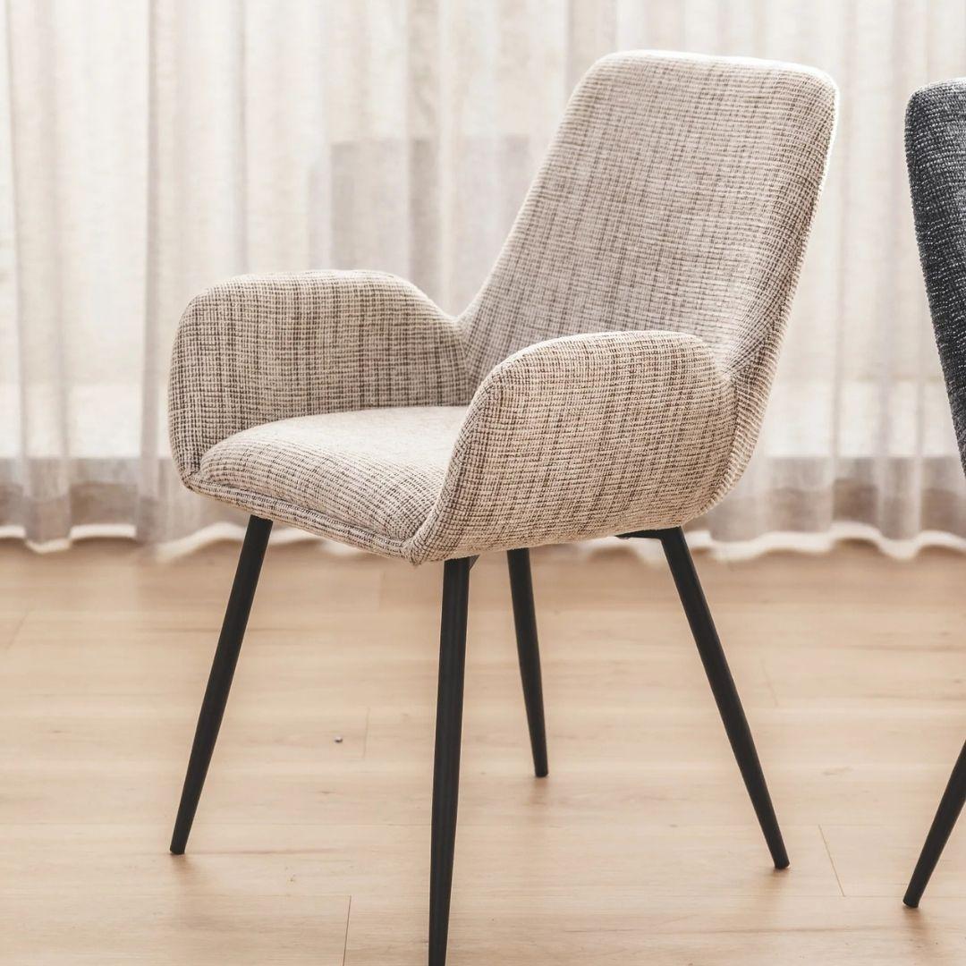 margot upholstered dining chair with black legs on a wooden floor with sheer curtains in the background