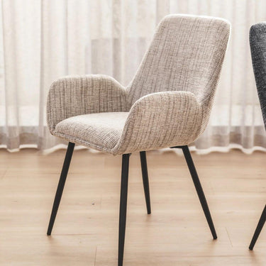 margot upholstered dining chair with black legs on a wooden floor with sheer curtains in the background