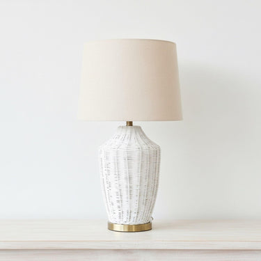 Mira white woven lamp styled on a console table highlighting its crisp organic texture and sophisticated metallic detail stand.