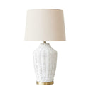 white rattan table lamp with a brass base and neutral fabric drum shade for coastal bedroom decor.