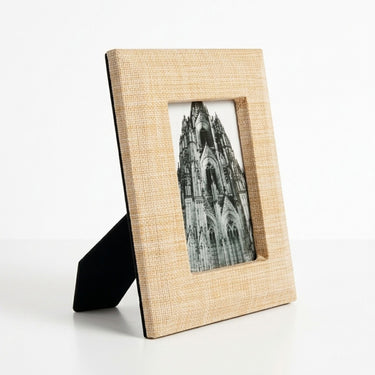 Rectangular picture frame with a light beige woven-texture border and a black stand.