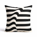 A square scatter cushion with a black and white graphic pattern featuring horizontal stripes that warp into fluid waves down the center.