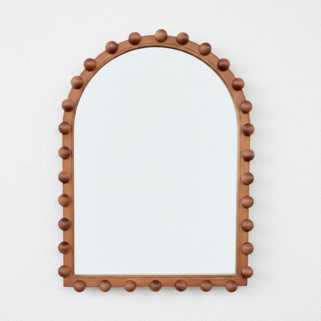 The Orla Arched Mirror, a wooden arch wall mirror with a handcrafted bobbin ball frame in a rich walnut finish