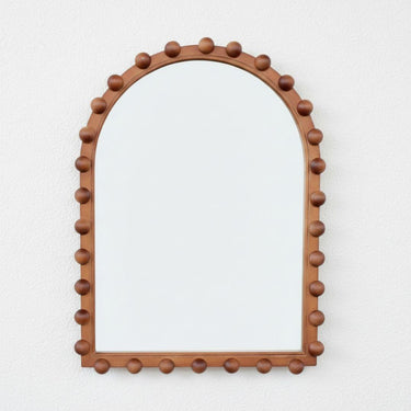 The Orla Arched Mirror, a wooden arch wall mirror with a handcrafted bobbin ball frame in a rich walnut finish