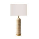 travertine table lamp with a cylindrical e base, a brass gold-finished neck and bottom cap, and a large white drum shade.