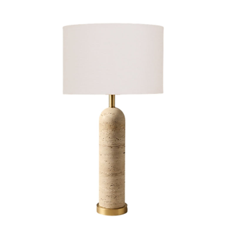 travertine table lamp with a cylindrical e base, a brass gold-finished neck and bottom cap, and a large white drum shade.