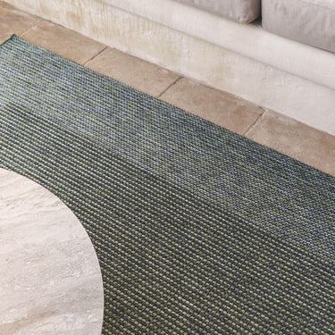  Green Pridelands outdoor rug with a two-toned design and bold border, on a sunlit patio.