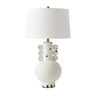 A ceramic table lamp with a white drum shade, a textured distressed base.