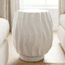Ripple side table with wavy ridged texture base in glossy white ceramic styled in a living room.