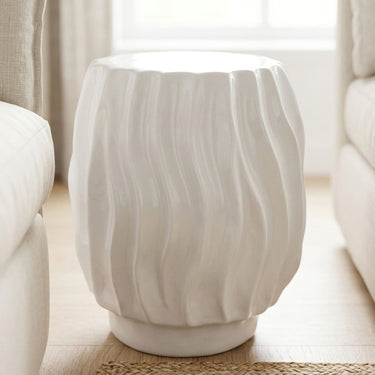 Ripple side table with wavy ridged texture base in glossy white ceramic styled in a living room.