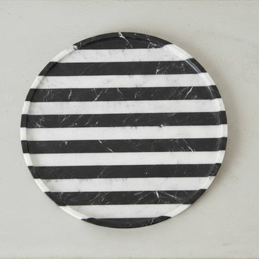 Round black marble tray shown from above with horizontal stripes