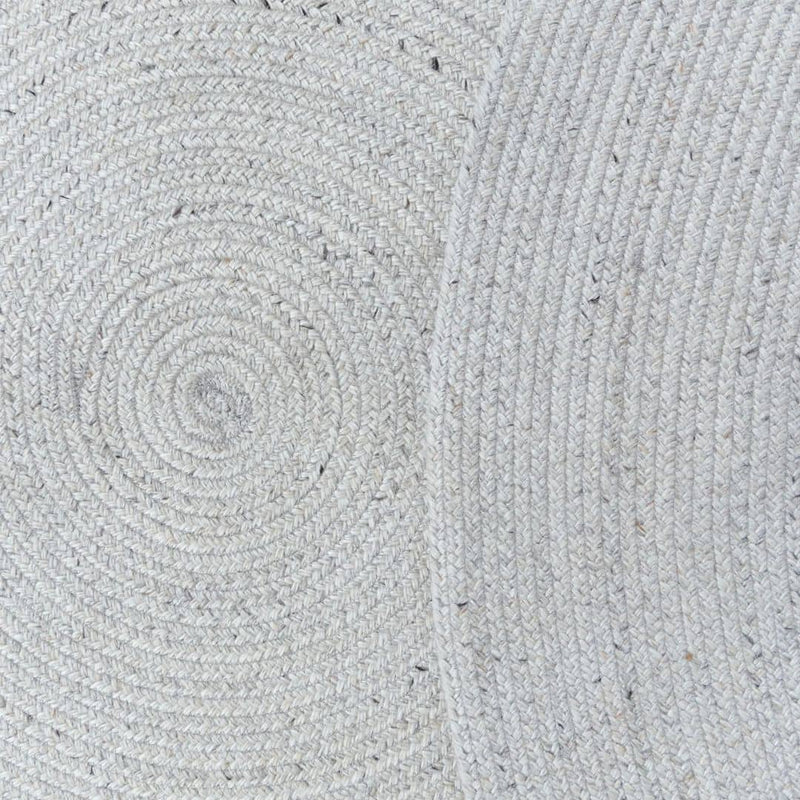 Close-up of a textured gray fabric on the Carousel Round Outdoor Rug in Creme