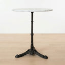 Round white marble bistro table with a black cast iron pedestal base.