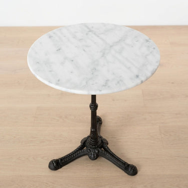 Round white marble bistro table with a black cast iron pedestal base.