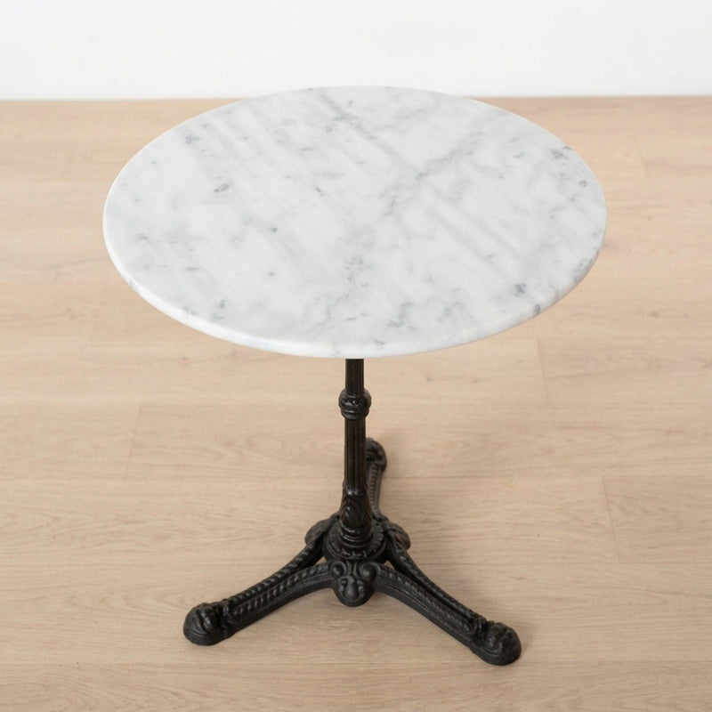 Round white marble bistro table with a black cast iron pedestal base.