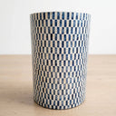 A drum side table with a blue and white checkered pattern, standing on a light wood surface against a white background.
