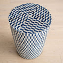 A round cylindrical accent table with a blue and white colour pattern on a light wood floor.
