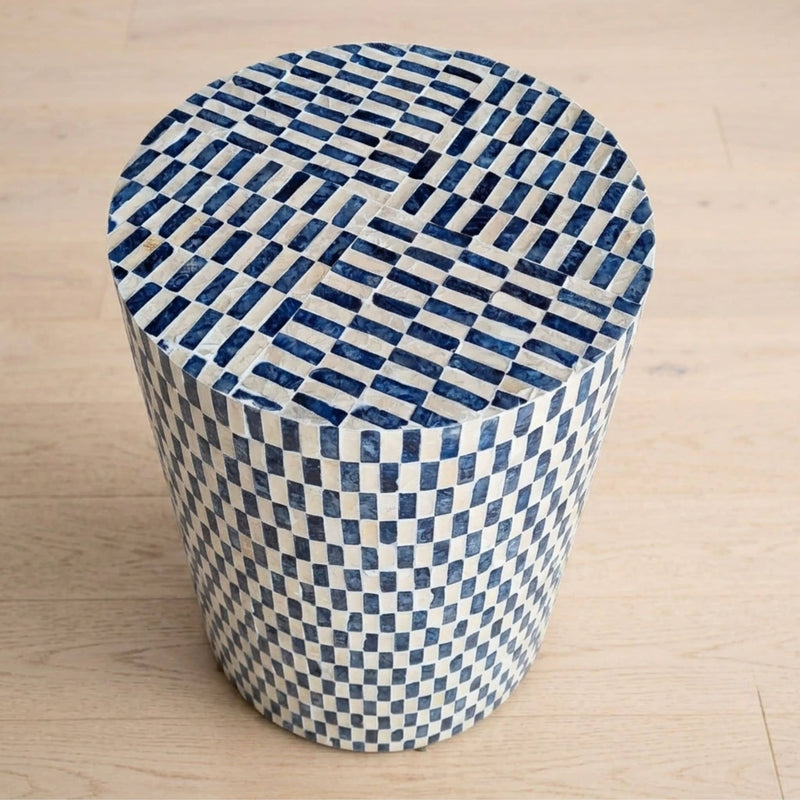 A round cylindrical accent table with a blue and white colour pattern on a light wood floor.