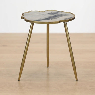 living room side table with a scalloped white and gray marble effect top and tripod gold metal legs.