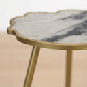 Close-up of a cloud-shaped side table with a white and gray marbled  effect top and a brushed gold metal frame.