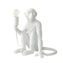 A white monkey-shaped table lamp holding an exposed Edison-style light bulb, shown on a plain white background.