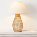 Rattan minimalist lamp illuminated on a side table showing the warm diffused glow through a beige fabric shade