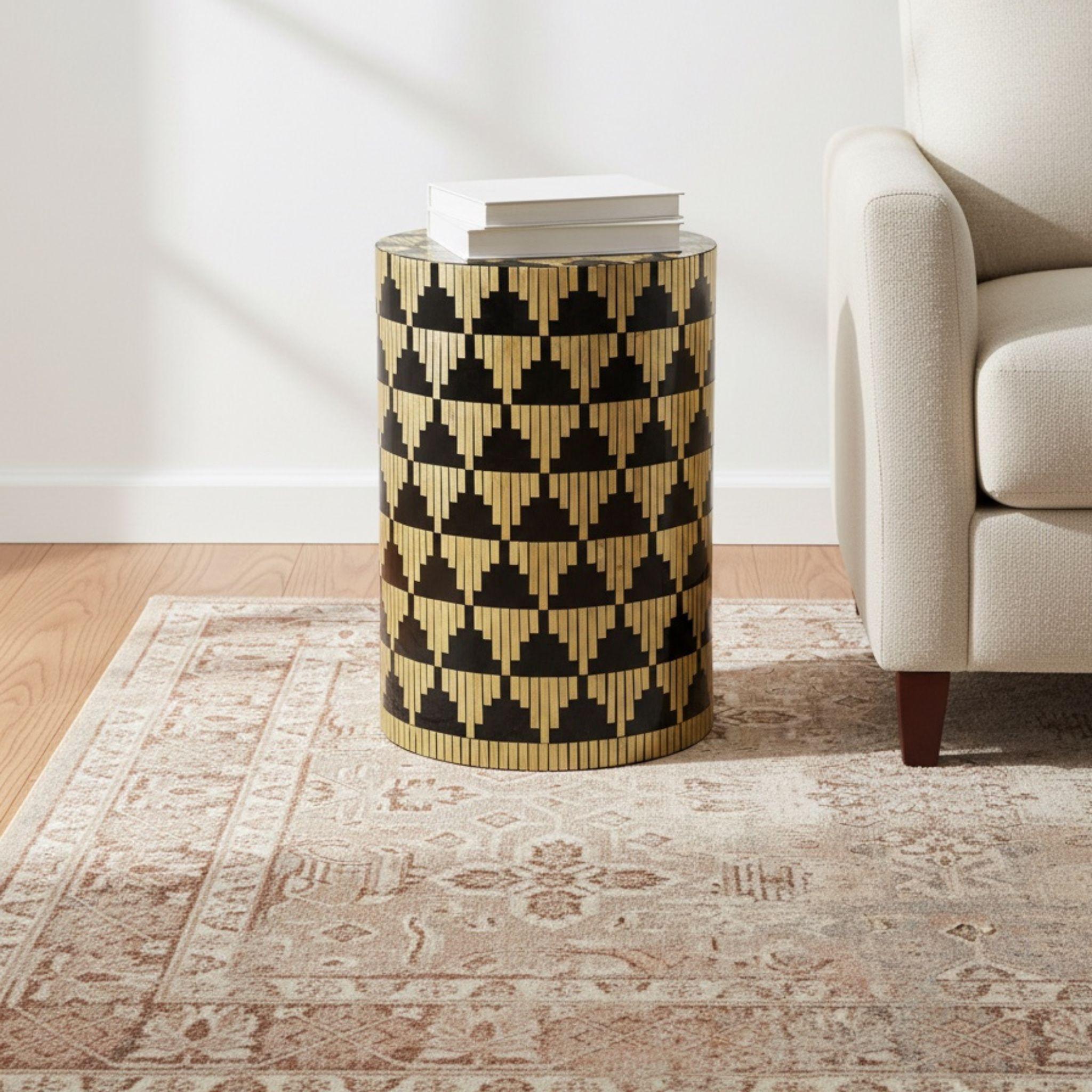 Modern geometric mother of pearl accent table styled on a rug next to a sofa in a minimalist living room.