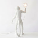 A white monkey-shaped table lamp holding a clear glass bulb, photographed against a clean white background.