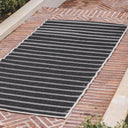 Swimsuit Night Dip reversible striped runner rug showing the dark charcoal side on an outdoor patio.