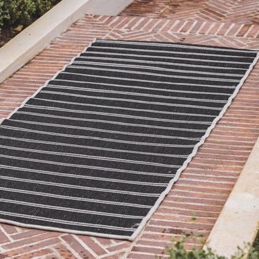 Swimsuit Night Dip reversible striped runner rug showing the dark charcoal side on an outdoor patio.