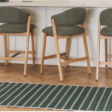 Swimsuit palmtops green striped runner rug on dark side on a kitchen floor.