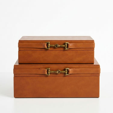 Two stacked rectangular  PU leather storage boxes in a warm tan-brown colour with a brass horsebit-style clasp closure.