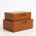 Two stacked rectangular brown faux-leather storage boxes with brass horsebit-style clasps.