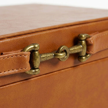 Close-up of a brown leather with a brass-toned buckle clasp and fine stitching on the tan decorative box.