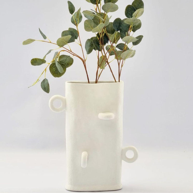 Tall flat white ceramic vase with loops, holding green eucalyptus branches