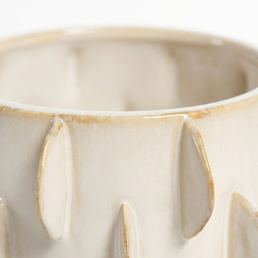 Close-up shot of the textured pattern and glossy warm ivory cream colour of the ceramic pot raised vertical ridges.
