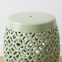 Close-up of the rounded top and open-work ceramic design on a sage green decorative barrel stool.