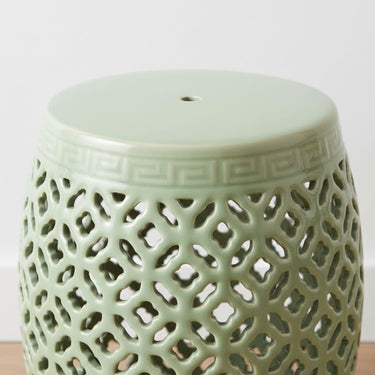 Close-up of the rounded top and open-work ceramic design on a sage green decorative barrel stool.