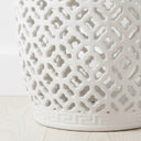Detailed view of the geometric cut-out pattern on a white glazed ceramic stool highlighting light and shadow play