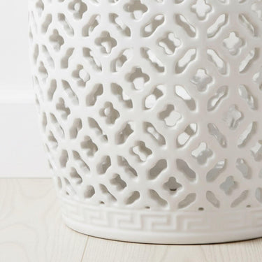 Detailed view of the geometric cut-out pattern on a white glazed ceramic stool highlighting light and shadow play