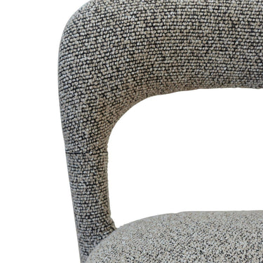 Close up of a textured fabric chair with a curved backrest and seat in a neutral speckled pattern of black and white.