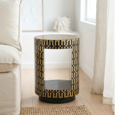 Living room side table with a black and bamboo geometric inlay pattern and a center opening panel, styled in a bright, modern living room next to a cream sofa.