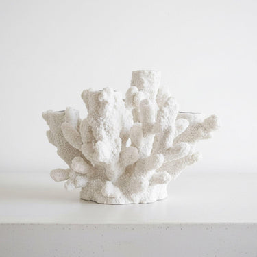 small  white coral tapered candle holder styled on a table 
