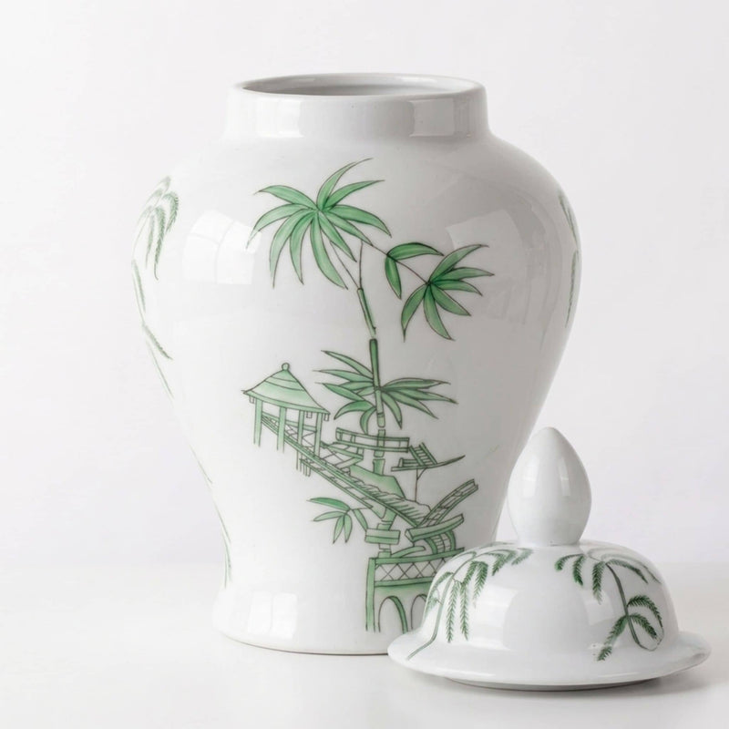 A white ceramic ginger jar with a matching lid, decorated with green bamboo and pagoda motifs, set against a plain white background.
