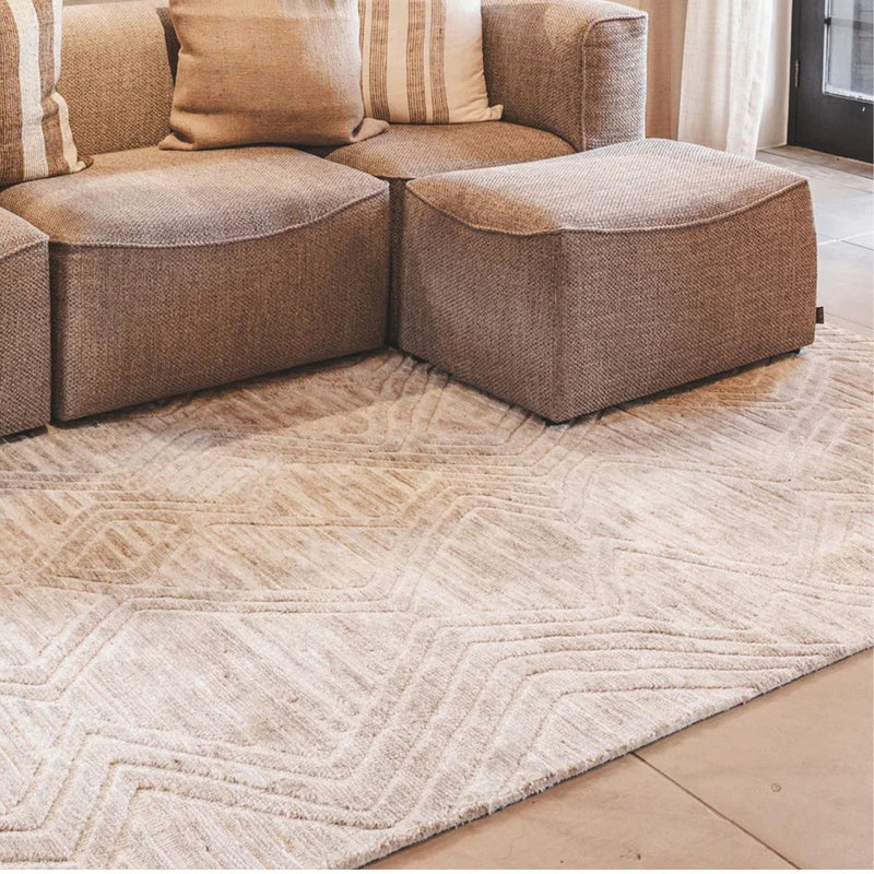 A large Xanadu area rug styled under furniture in a living room, highlighting its geometric tribal design.