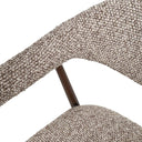 Close-up of coco dark textured boucle-style fabric upholstery and curved wraparound armrest and dark supportive frame.
