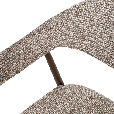 Close-up of coco dark textured boucle-style fabric upholstery and curved wraparound armrest and dark supportive frame.
