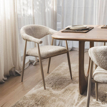 Set of Yvette oats boucle style dining chairs around a modern wooden dining room table.