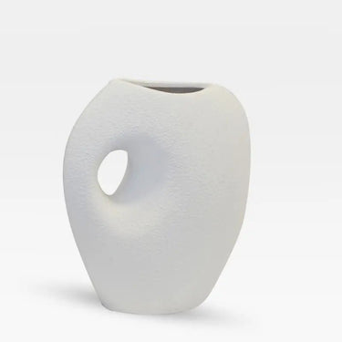Matte white ceramic vase with rough texture, sculptural side detail, and wide opening for long stems